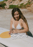 Model on beach in California with surfboard and water resistant Everything Beach Bag