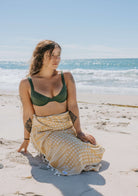 Model in swimsuit on the beach wrapped up with Turkish towel